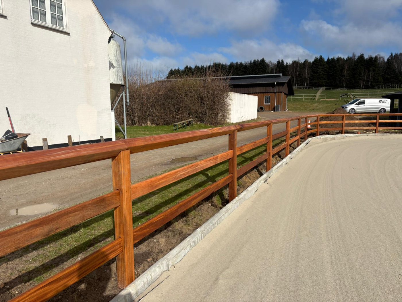 Post and rail fence enclosing a sand riding arena