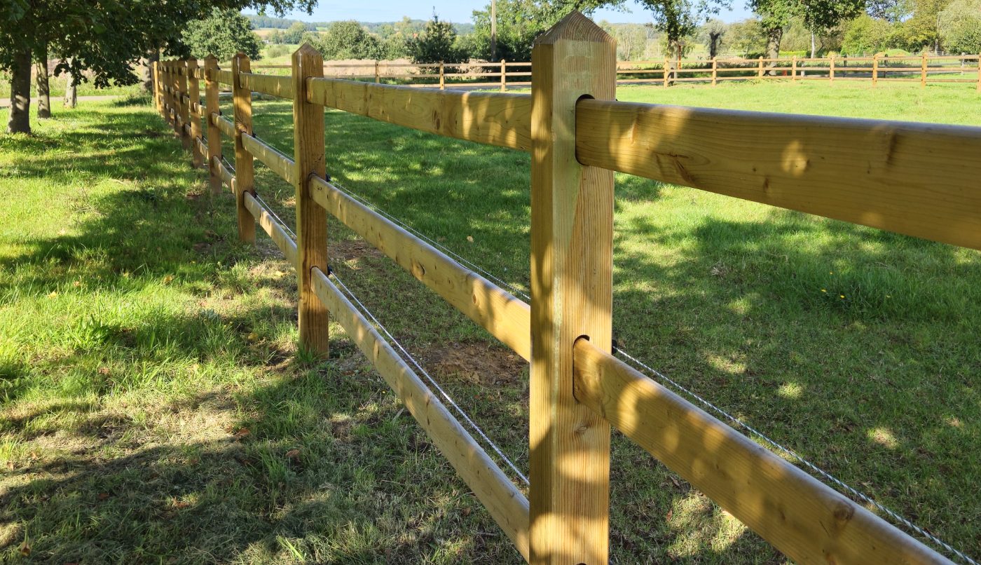 Post and rail fence in golden light with integrated wire