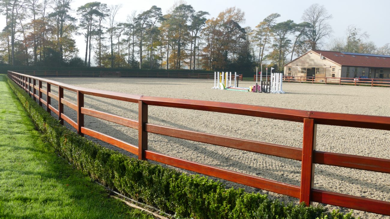 Wooden perimeter fencing around a riding arena