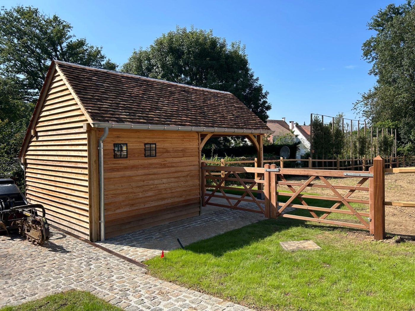 Custom hardwood gates beside an oak carriage house