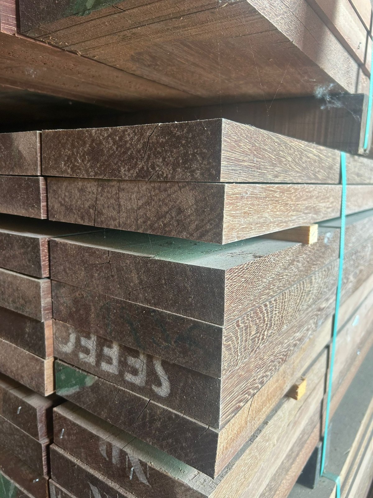 Dense dark Azobé hardwood posts stacked in the warehouse